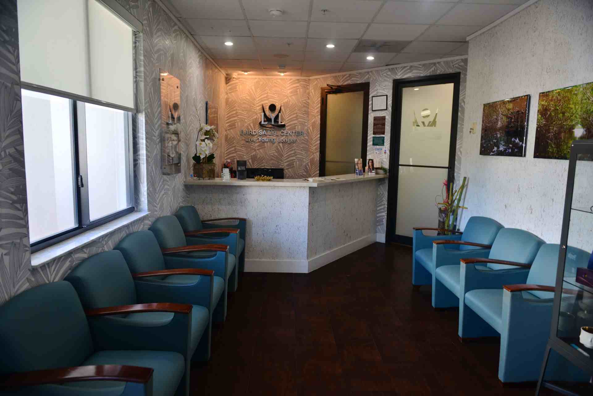 Waiting room with blue chairs, white counter and paintings on the white wall